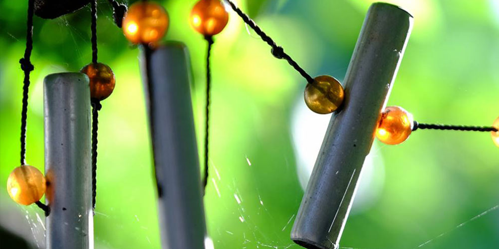 close up of metal windchime with beading decoration in garden